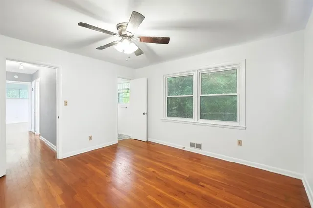 a view of an empty room with wooden floor and a window