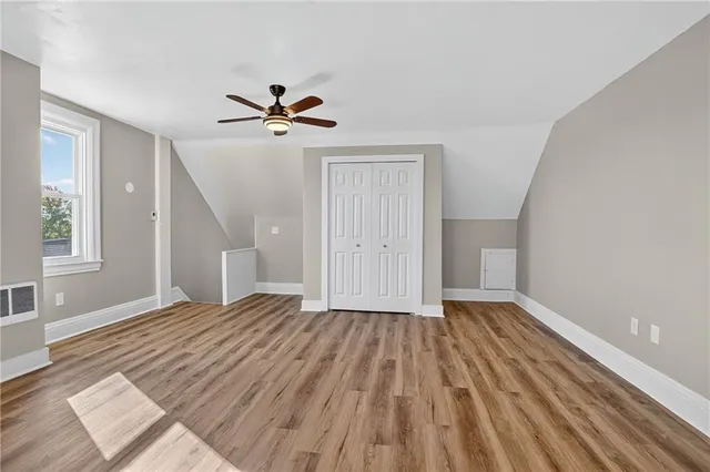 a view of empty room with wooden floor and fan