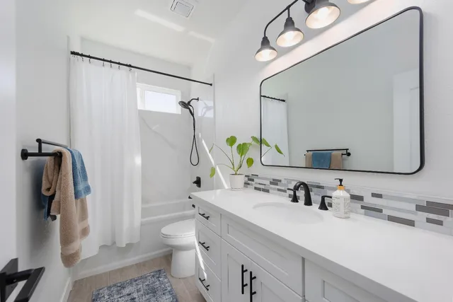 a bathroom with a sink vanity granite toilet and shower