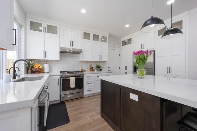 a kitchen with a sink dishwasher stove and white cabinets with wooden floor