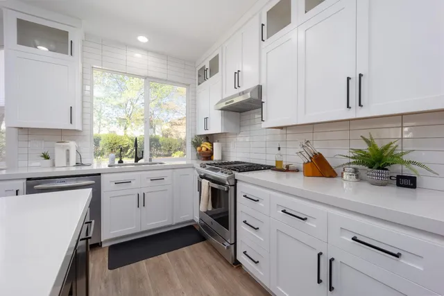 a kitchen with white cabinets a sink and appliances