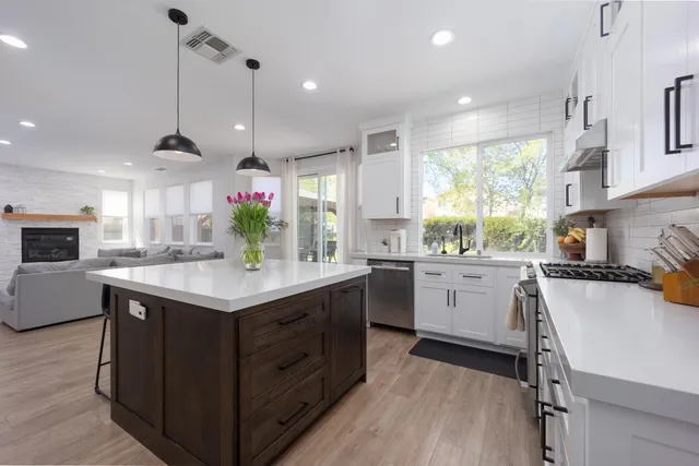 a kitchen with a stove a sink a center island and windows