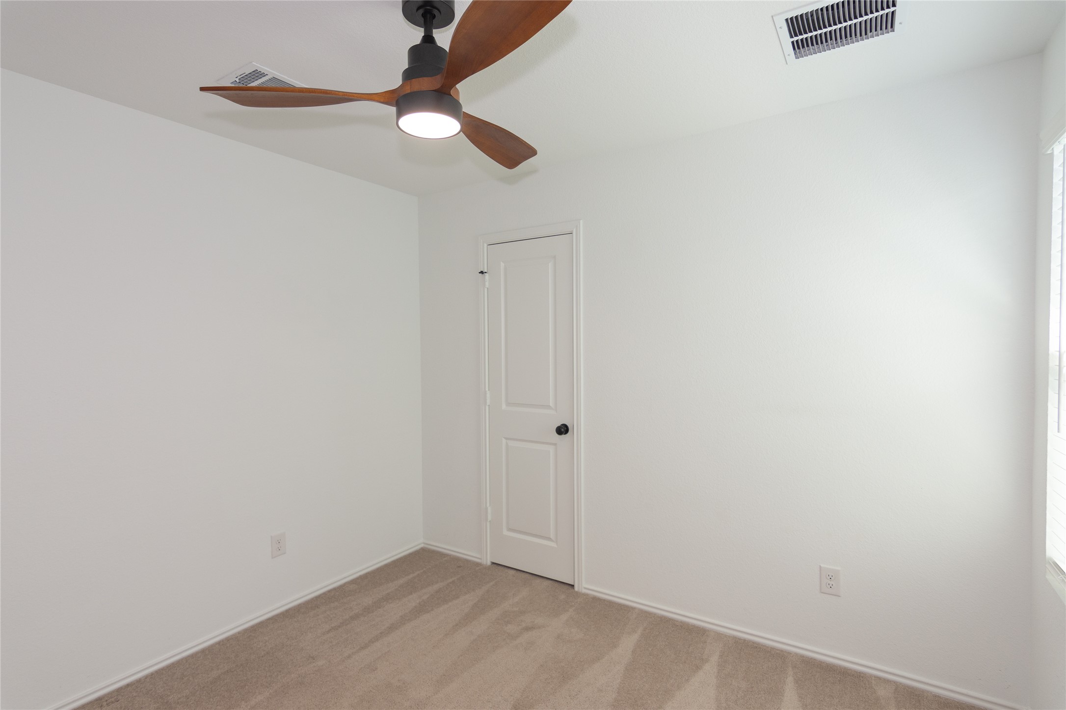 548 Rancho Del Cielo Loop Jarrell, TX 76537 - Photo 21 of 40 Room featuring a modern ceiling fan with wood-finish blades and integrated lighting, neutral carpet flooring, white walls, and a window with horizontal blinds