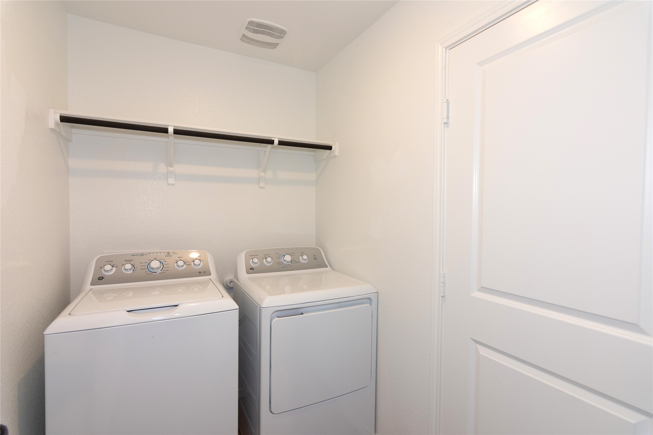 548 Rancho Del Cielo Loop Jarrell, TX 76537 - Photo 25 of 40 Dedicated laundry area with a built-in hanging rod, wall shelving, white walls, and a white paneled door