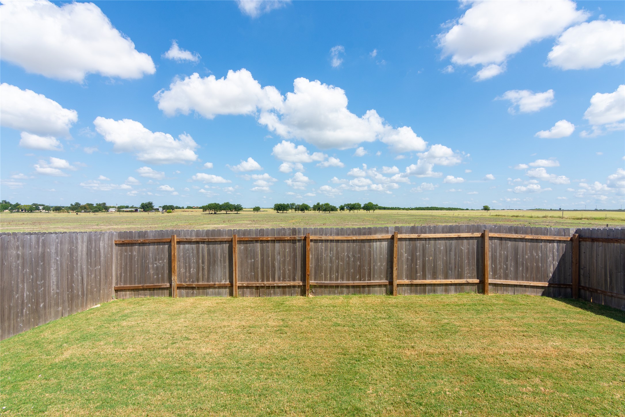 548 Rancho Del Cielo Loop Jarrell, TX 76537 - Photo 26 of 40 Expansive backyard featuring a wood privacy fence and a manicured lawn, bordered by open fields and distant trees