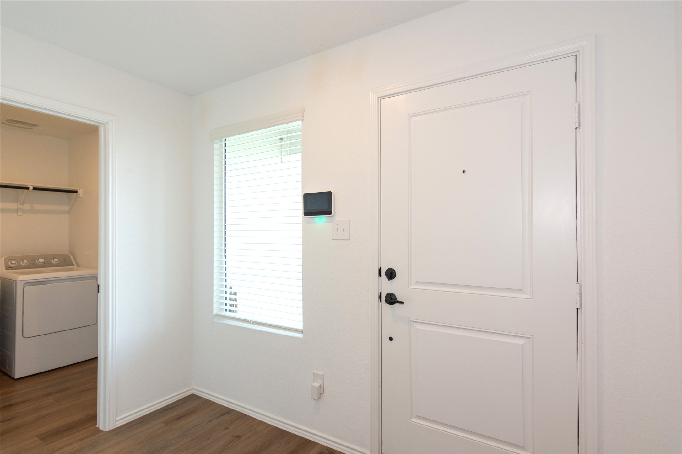 548 Rancho Del Cielo Loop Jarrell, TX 76537 - Photo 3 of 40 Entryway featuring a paneled door with matte black hardware, wood-finish flooring, and a window with horizontal blinds