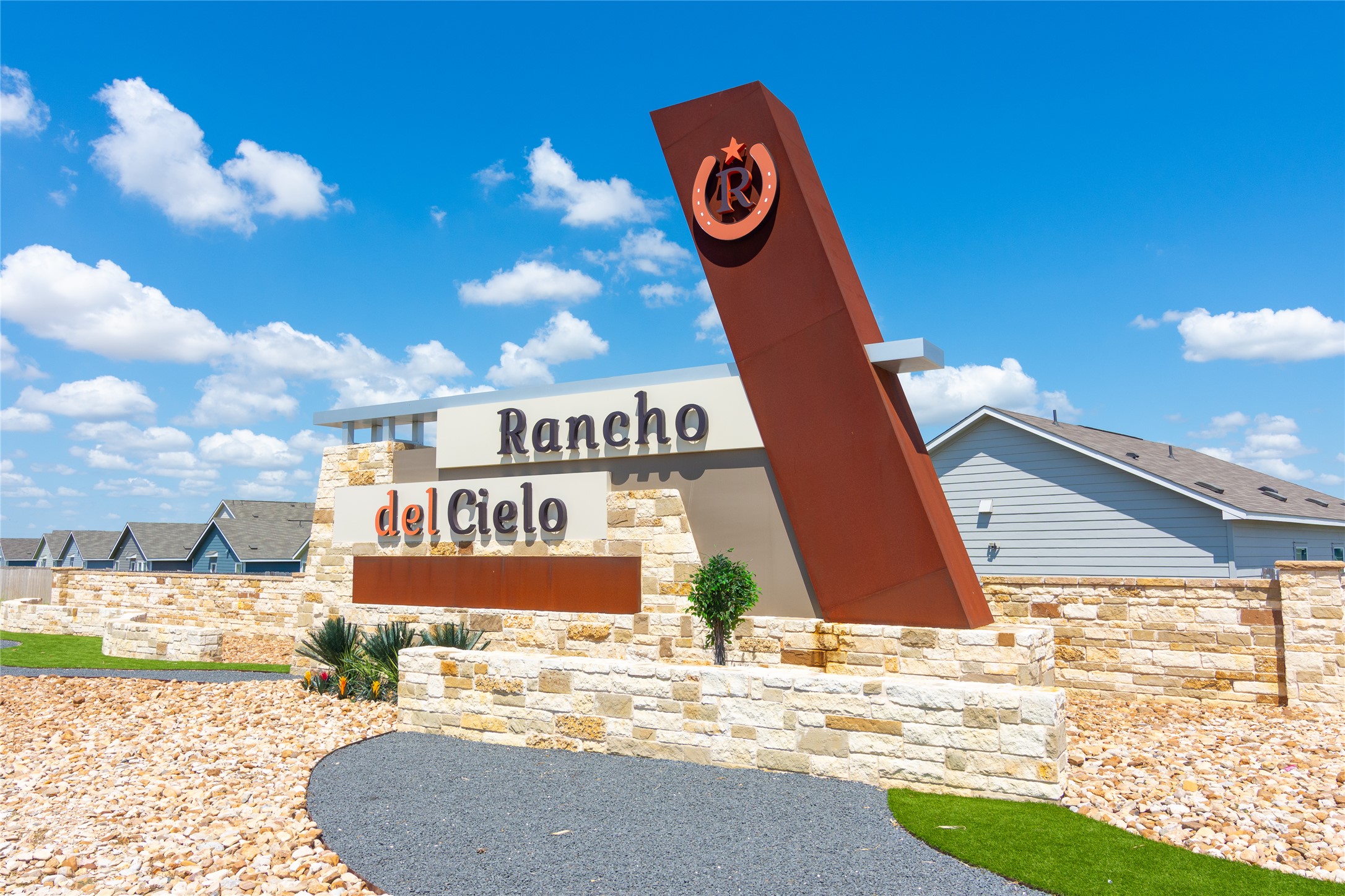 548 Rancho Del Cielo Loop Jarrell, TX 76537 - Photo 31 of 40 Community entrance featuring a stone wall, architectural signage, and a gravel pathway