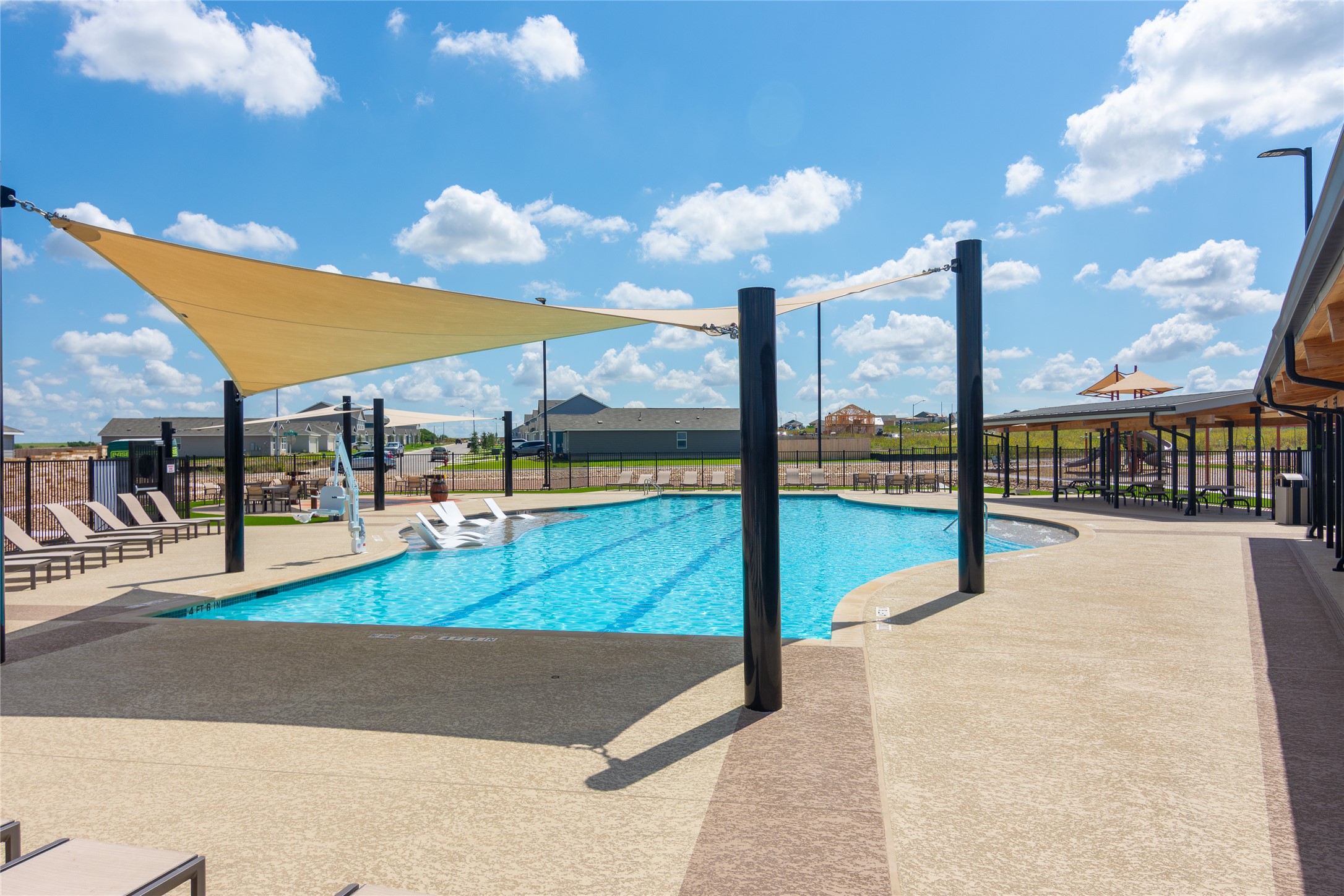 548 Rancho Del Cielo Loop Jarrell, TX 76537 - Photo 33 of 40 Expansive outdoor swimming pool featuring a curved design, sunshade sails, a wide concrete deck, and a covered pavilion structure