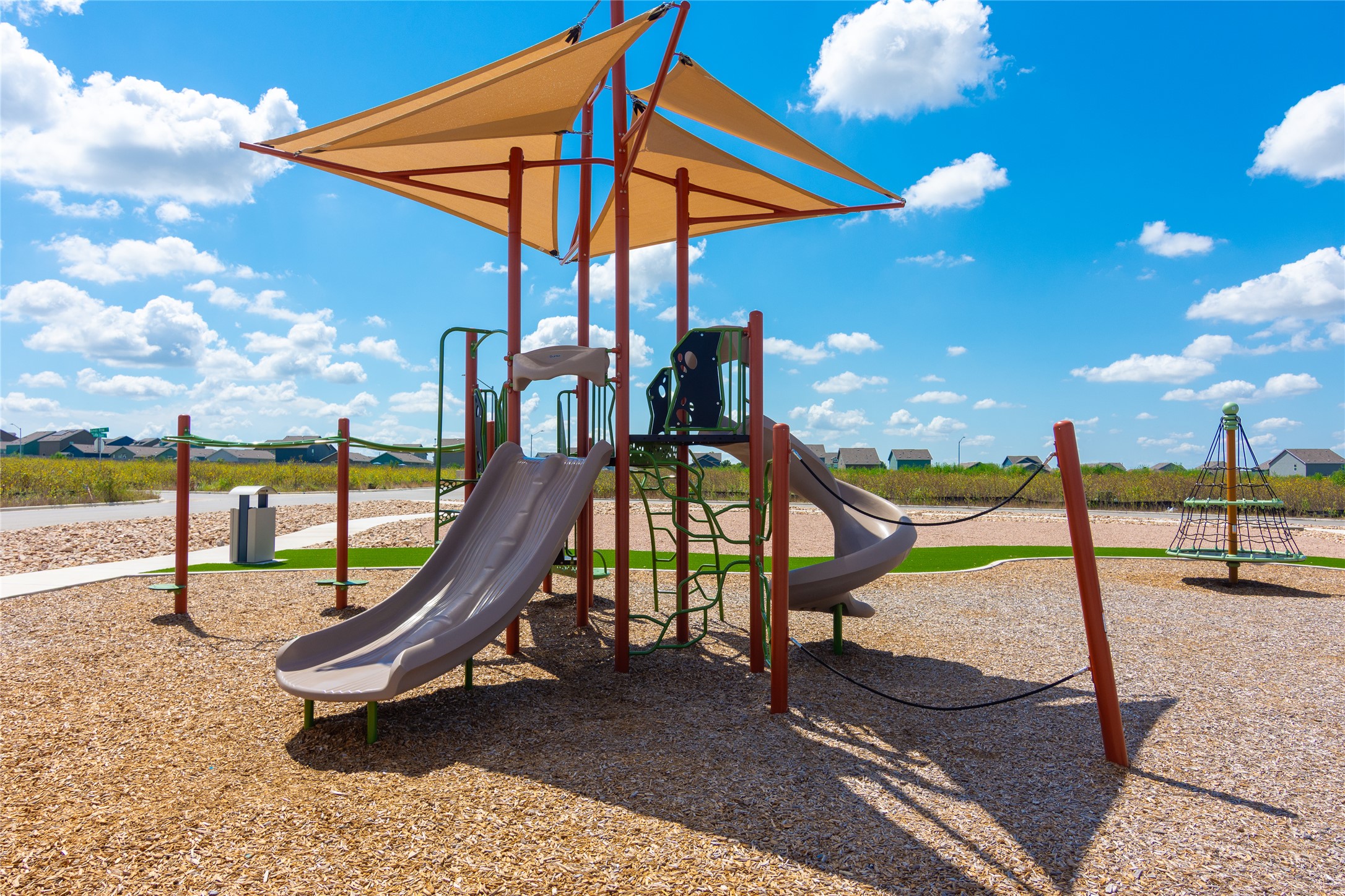 548 Rancho Del Cielo Loop Jarrell, TX 76537 - Photo 36 of 40 Community playground featuring shade canopies, multiple slides, a climbing structure, and a separate rotating play apparatus