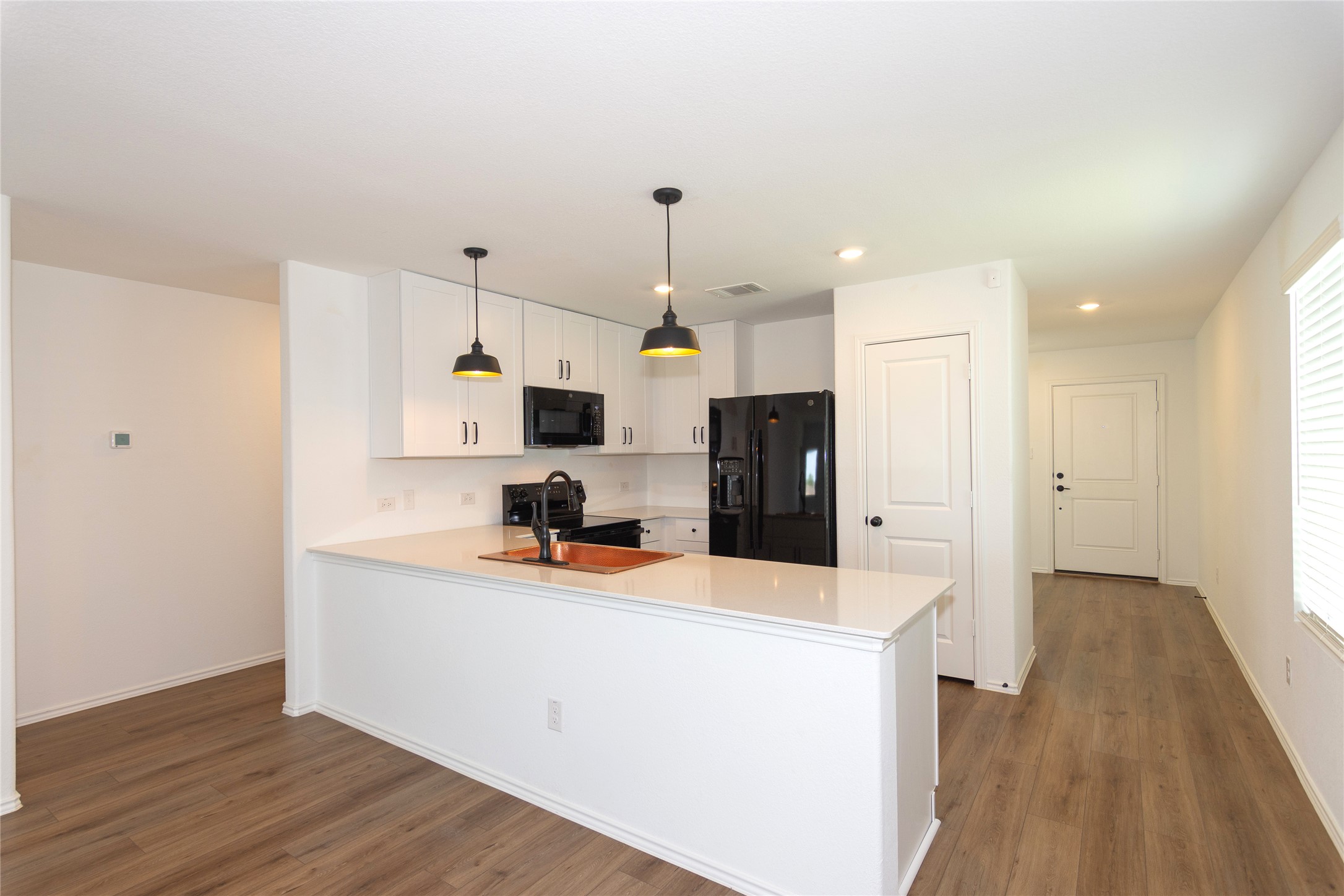 548 Rancho Del Cielo Loop Jarrell, TX 76537 - Photo 4 of 40 Contemporary kitchen featuring white cabinetry, black appliances, quartz countertops, and two pendant lights over the island
