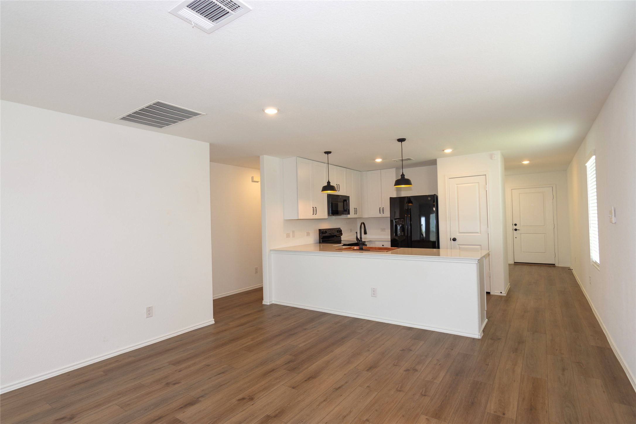 548 Rancho Del Cielo Loop Jarrell, TX 76537 - Photo 8 of 40 Open-concept living area featuring wood-finish flooring, white walls, and a recessed ceiling vent