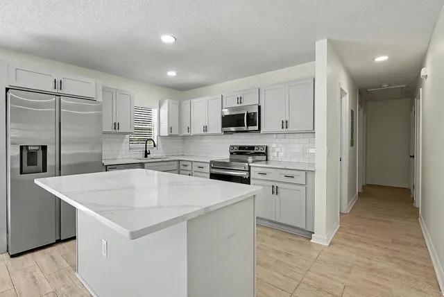 a kitchen with kitchen island a sink stove and refrigerator