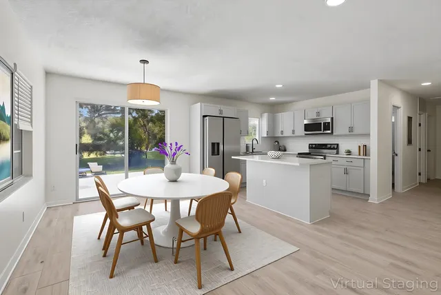 a kitchen with kitchen island a dining table chairs stainless steel appliances and cabinets