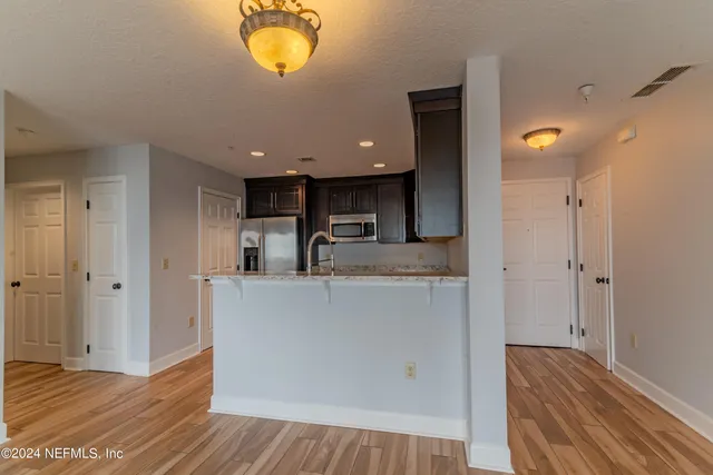 a view of kitchen with stainless steel appliances granite countertop a refrigerator and a microwave