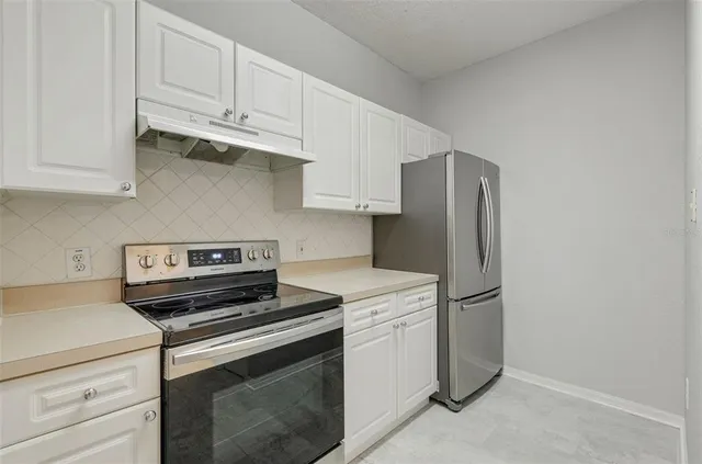 a kitchen with stainless steel appliances white cabinets and a refrigerator