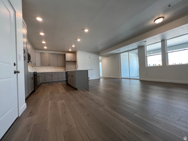 717 West W Coho Lane South, Unit 2F302 Midvale, UT 84047 - Photo 3 of 22 Open-concept living area featuring wood-finish flooring, a contemporary kitchen with gray cabinetry, white countertops, and a kitchen island