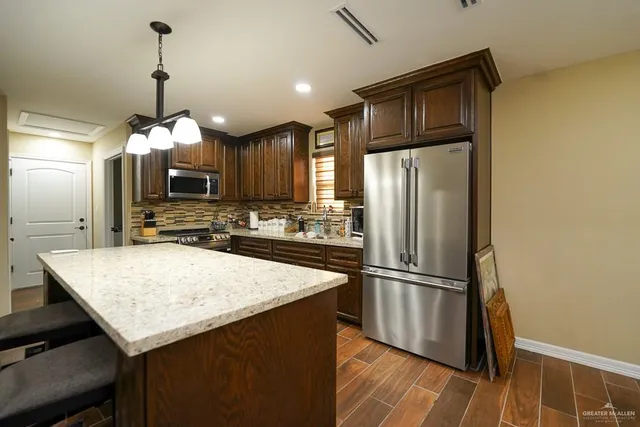 a kitchen with granite countertop a refrigerator and a stove top oven