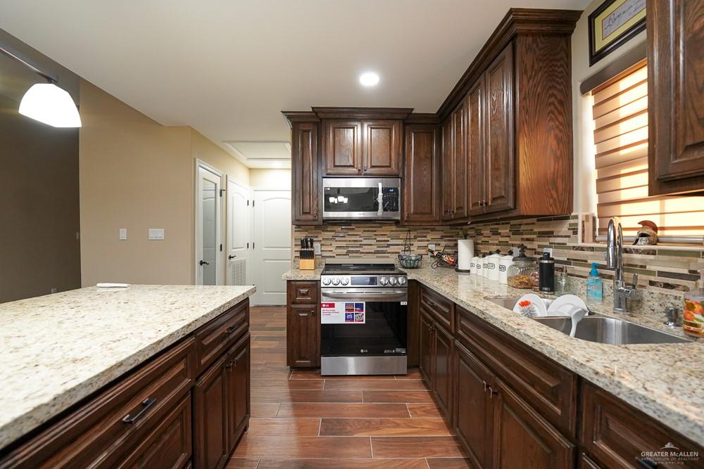 1408 Royola Street Mission, TX 78572 - Photo 15 of 42 a kitchen with stainless steel appliances granite countertop wooden cabinets a sink and dishwasher