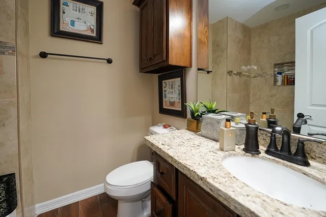 a bathroom with a granite countertop toilet sink and mirror