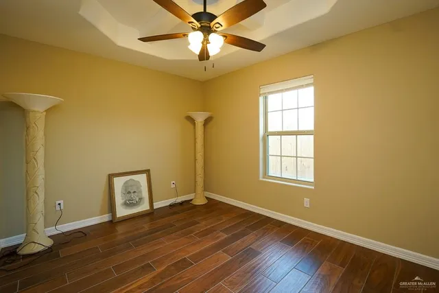 a view of an empty room with window and wooden floor