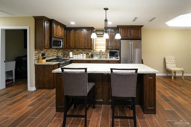 a kitchen with stainless steel appliances a dining table chairs and sink