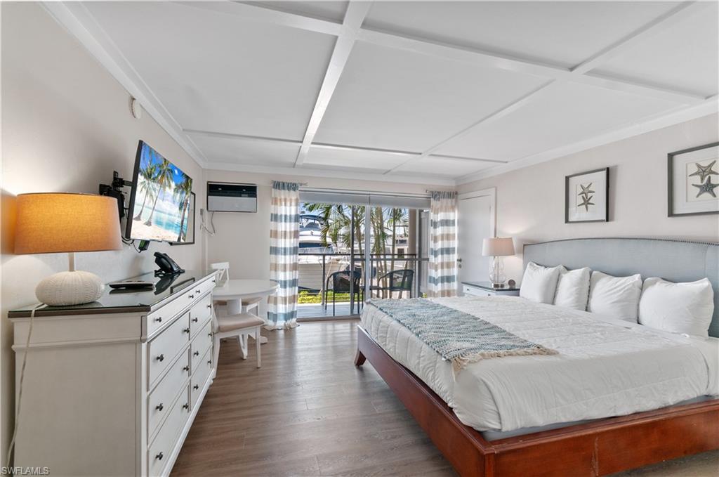 900 Broad Avenue South, Unit 133/134 Naples, FL 34102 - Photo 16 of 37 a spacious bedroom with a bed and wooden floor