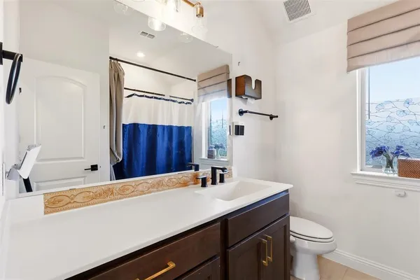a bathroom with a sink a toilet a mirror and shower