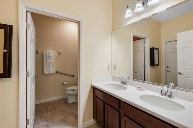 a bathroom with a double vanity sink toilet and a mirror