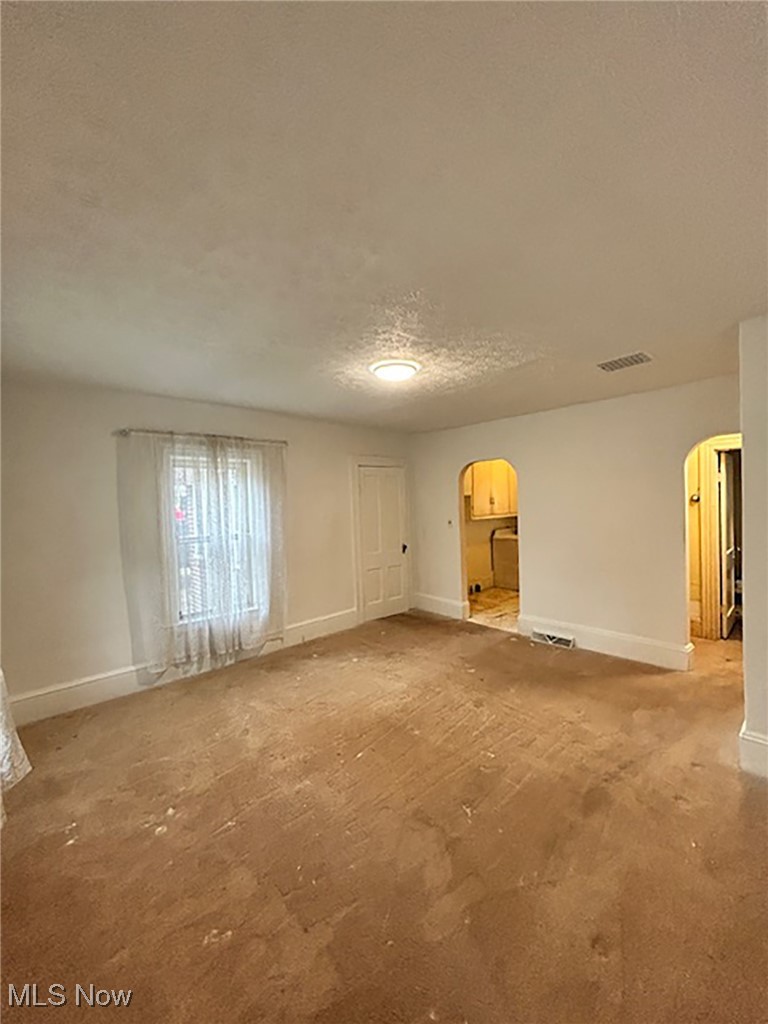 6128 Riverview Road Peninsula, OH 44264 - Photo 5 of 17 Unfurnished living room featuring a textured ceiling, arched walkways, and carpet floors