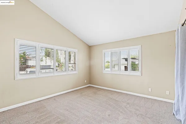 an empty room with wooden floor a chandelier fan and windows
