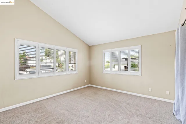 an empty room with wooden floor a chandelier fan and windows