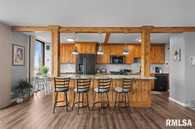 a kitchen with stainless steel appliances a dining table chairs and wooden floor