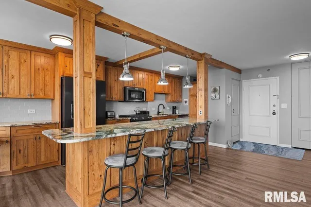 a kitchen with stainless steel appliances granite countertop a kitchen island a stove a cabinets and a chair