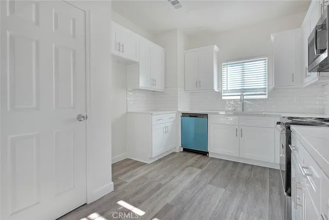 a kitchen with white cabinets and black appliances