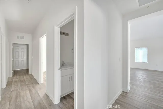 a view of an empty room with wooden floor and a ceiling fan