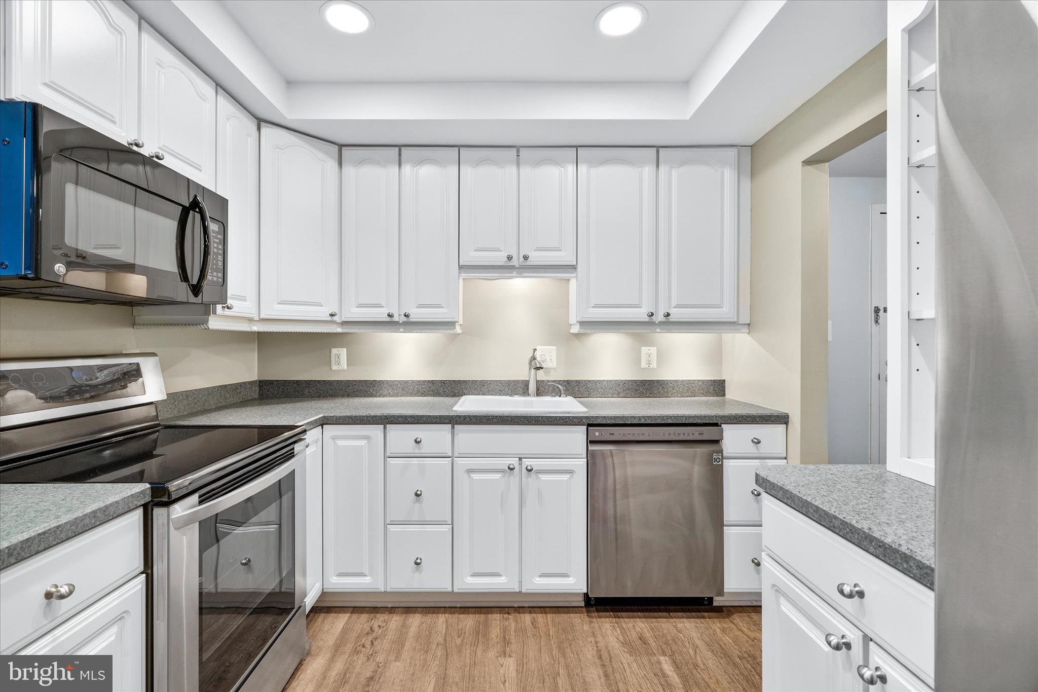 10000 Stedwick Road, Unit 104 Montgomery Village, MD 20886 - Photo 10 of 31 a kitchen with stainless steel appliances granite countertop a stove a sink and a microwave
