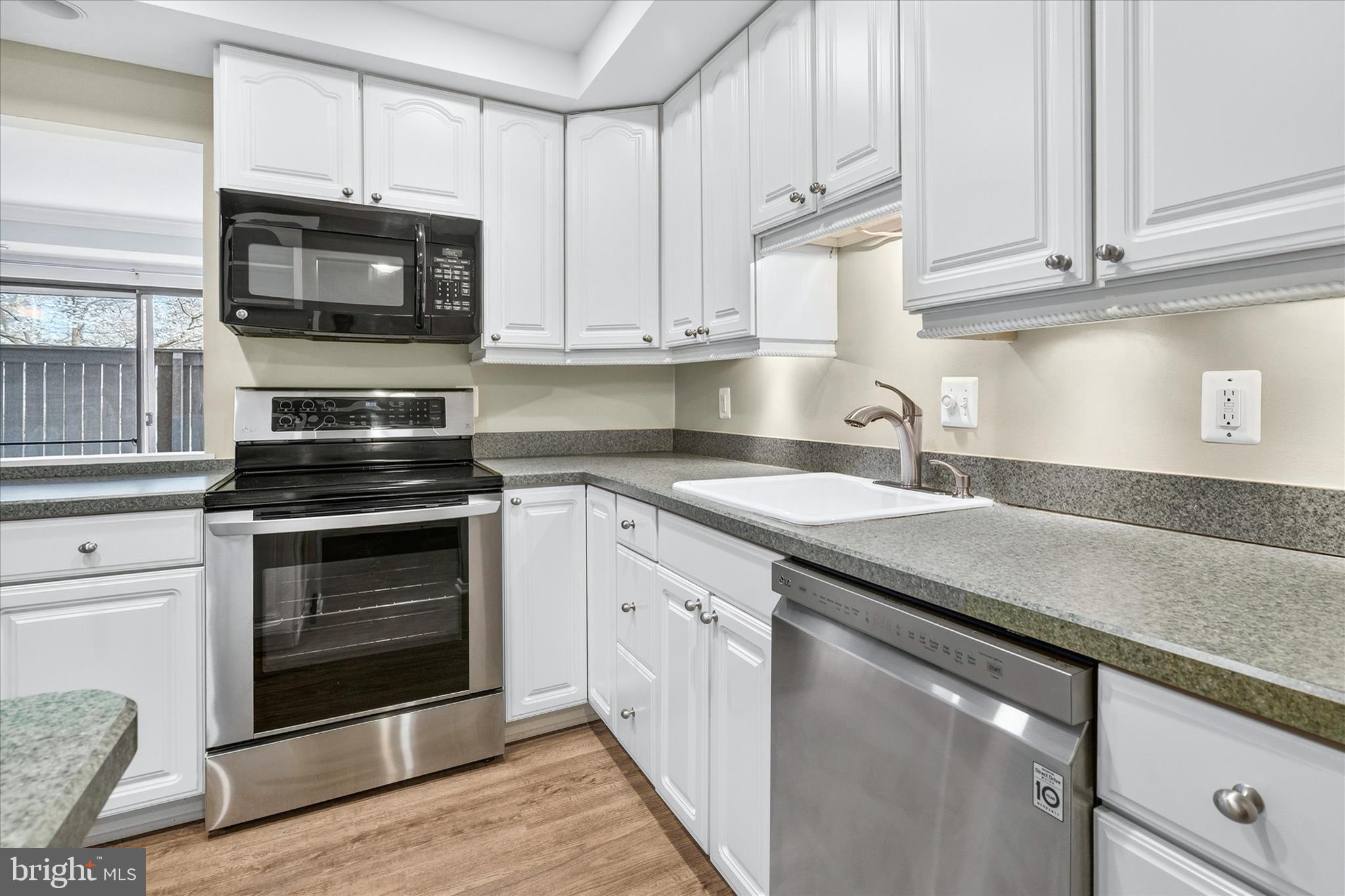 10000 Stedwick Road, Unit 104 Montgomery Village, MD 20886 - Photo 11 of 31 a kitchen with granite countertop a stove microwave and sink