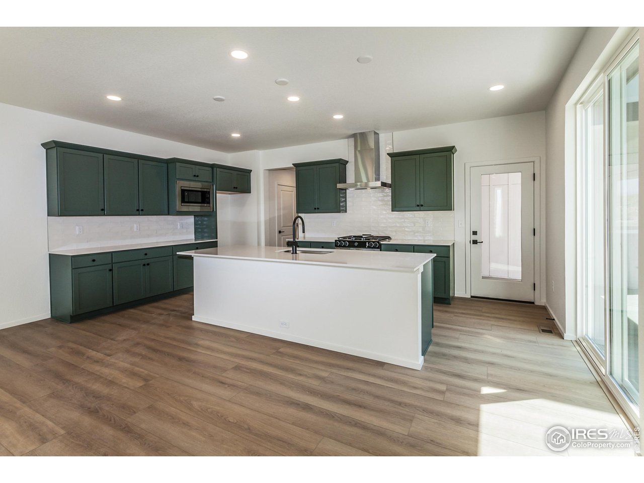 6126 Red Barn Road Fort Collins, CO 80528 - Photo 5 of 36 a view of kitchen with stainless steel appliances kitchen island a stove a refrigerator a microwave oven with cabinets and wooden floor