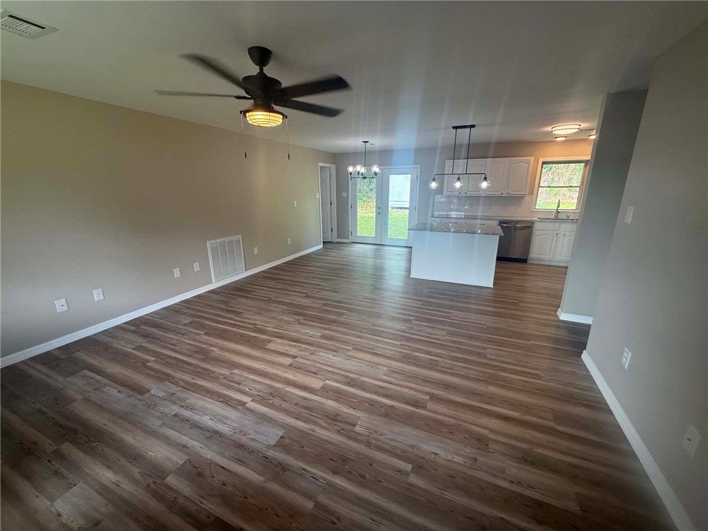 2106 Military Road Dardanelle, AR 72834 - Photo 2 of 16 Open-concept living space featuring wood-finish flooring, a ceiling fan, a kitchen island, pendant lighting, and French doors