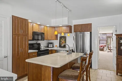 a kitchen with stainless steel appliances a sink a stove a refrigerator cabinets and chairs