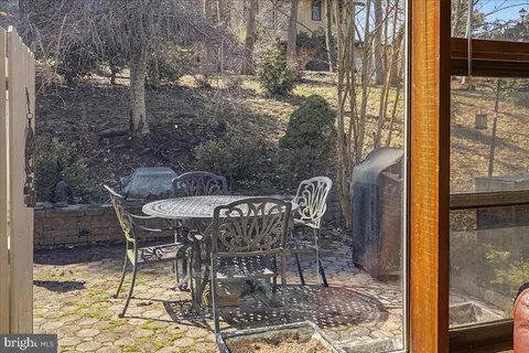 a patio with table and chairs and potted plants