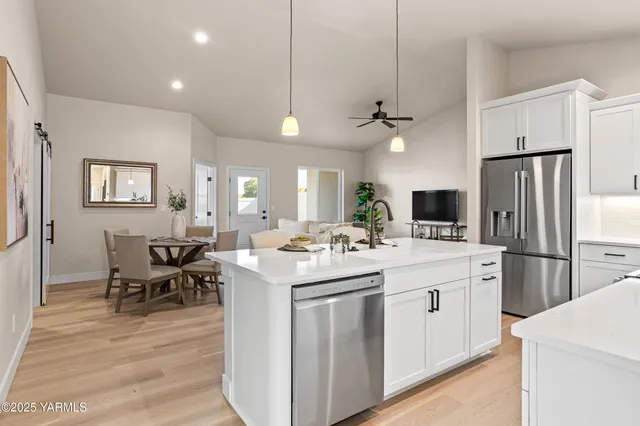 a kitchen with a sink a stove a refrigerator and white cabinets with wooden floor