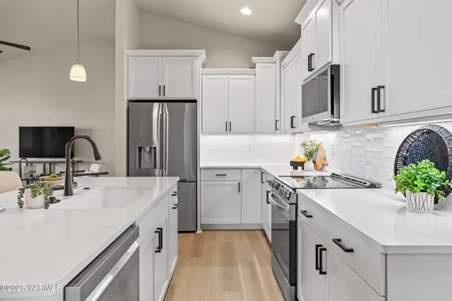 a kitchen with granite countertop a sink stainless steel appliances and white cabinets