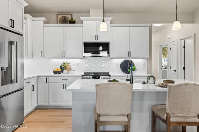 a kitchen with stainless steel appliances granite countertop a stove a refrigerator a white table and chairs