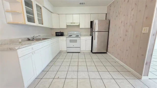 a kitchen with a refrigerator sink stove and cabinets