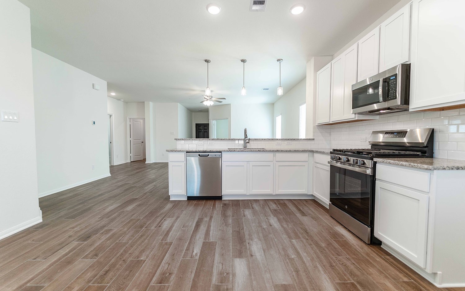 10656 Altitude Way Conroe, TX 77303 - Photo 7 of 30 a kitchen with stainless steel appliances a white stove top oven cabinets and a wooden floor