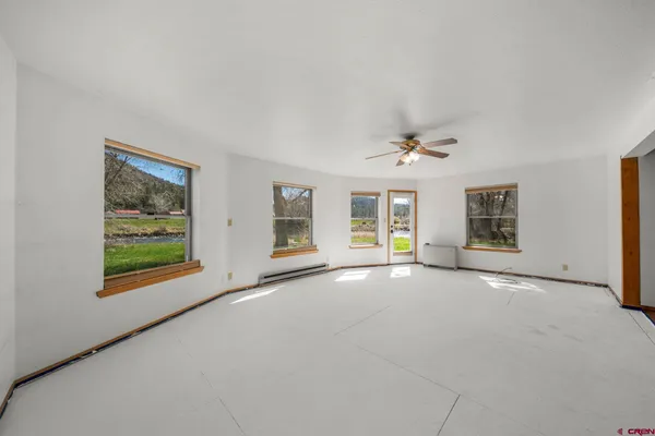 an empty room with windows and chandelier fan