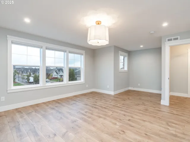 an empty room with wooden floor cabinet and windows