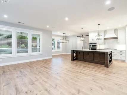 a large kitchen with stainless steel appliances kitchen island granite countertop a large window and a sink