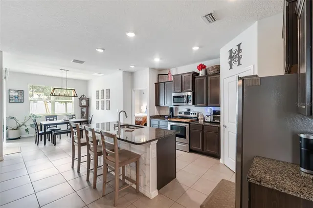 a kitchen with stainless steel appliances kitchen island granite countertop a table chairs stove and refrigerator